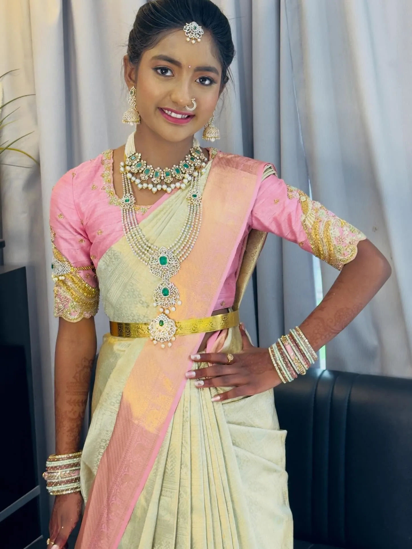 Teen client in pink and cream half-saree with green-stone jewellery, soft glam and mehndi