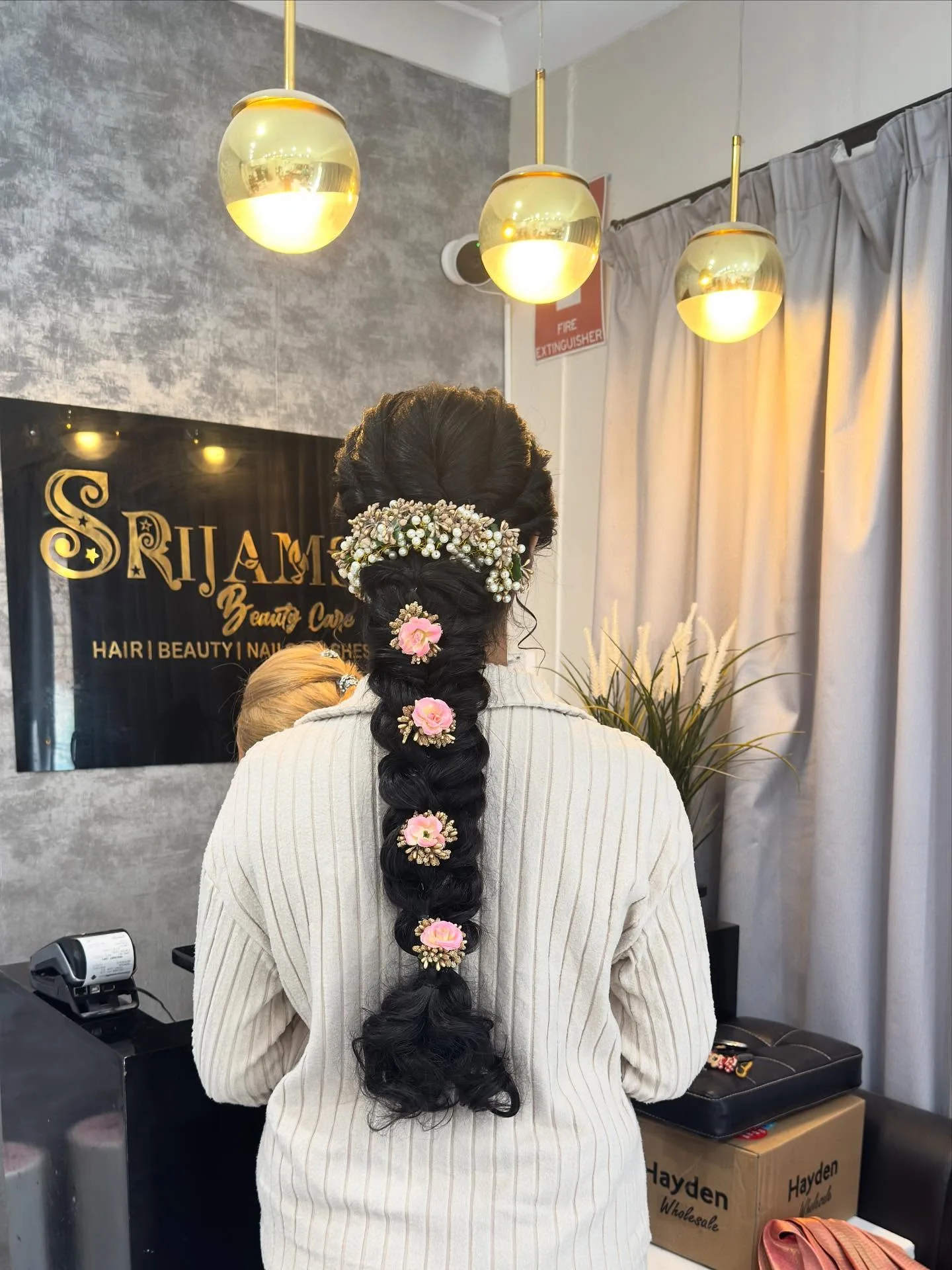Bridal braid dressed with pink roses and babys-breath crown, under gold pendant lights at the Srijams reception