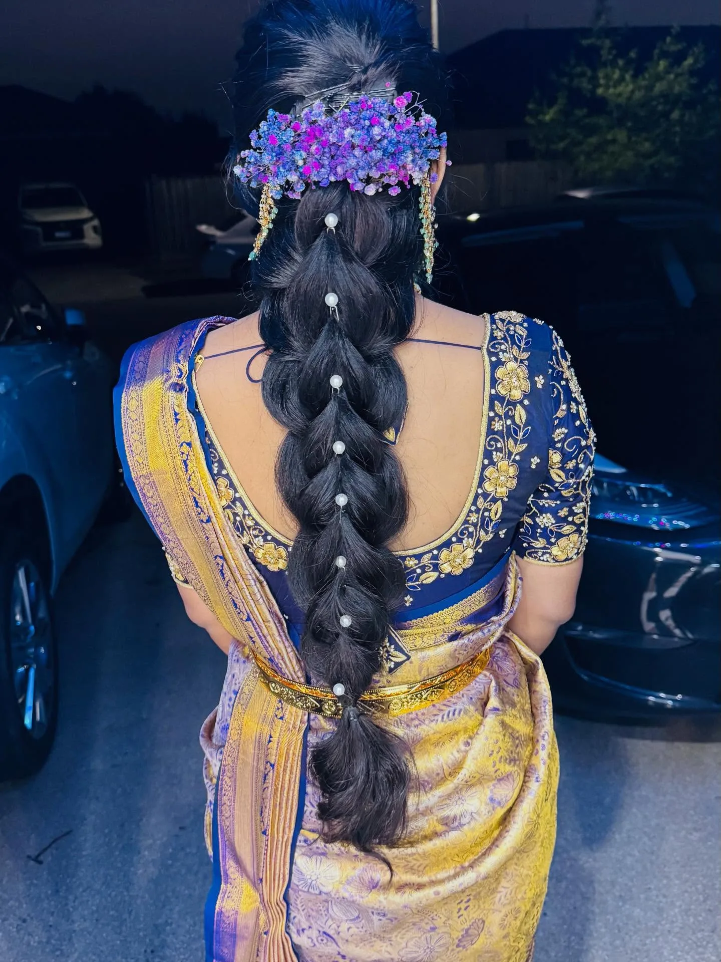 Rear view of pearl-and-babys-breath bridal braid, navy gold saree, photographed outdoors at night
