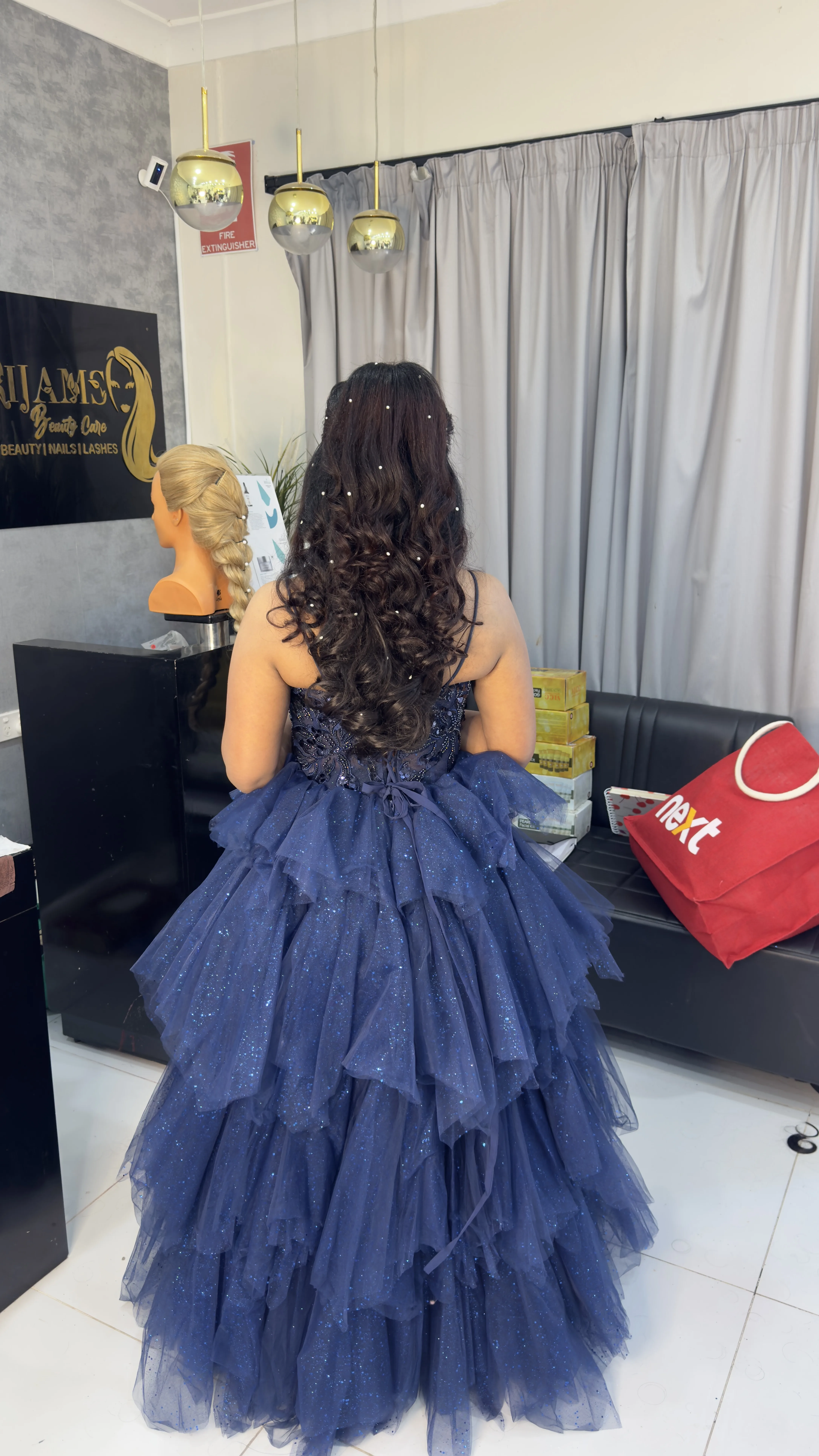 Rear view of pearl-set half-up curled up-style on a navy sparkle gown, by the Srijams plaque